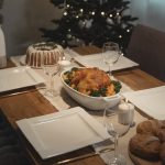 A beautifully set holiday dinner table with roast chicken and desserts, evoking warmth and celebration.