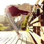 woman bending her body while holding metal bar